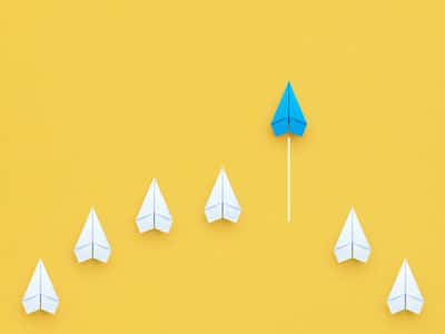 A group of paper airplanes forming a line on a yellow background.